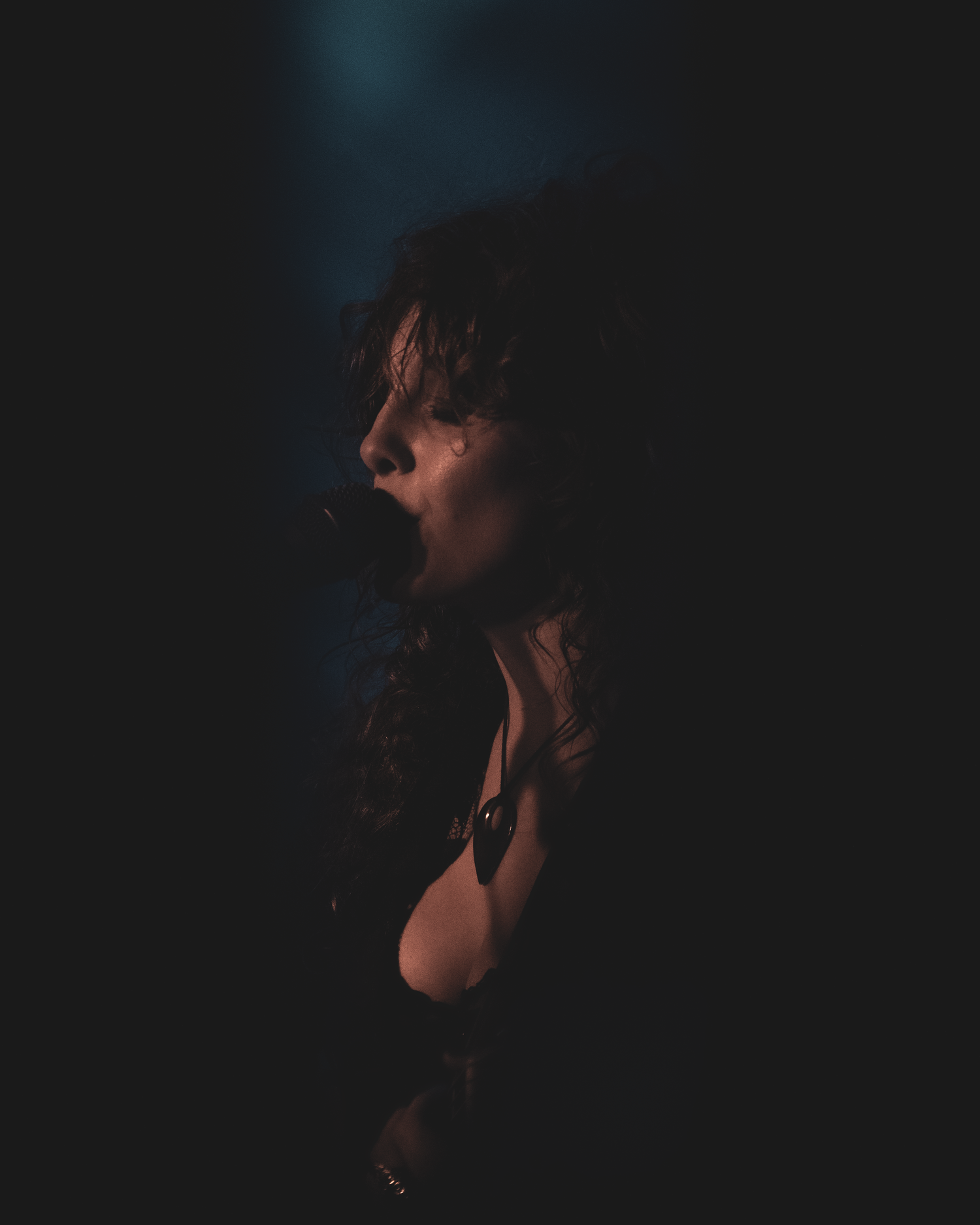 Heidi Curtis playing at The Cluny in Newcastle wearing a dark lace garment in a dimly lit setting
