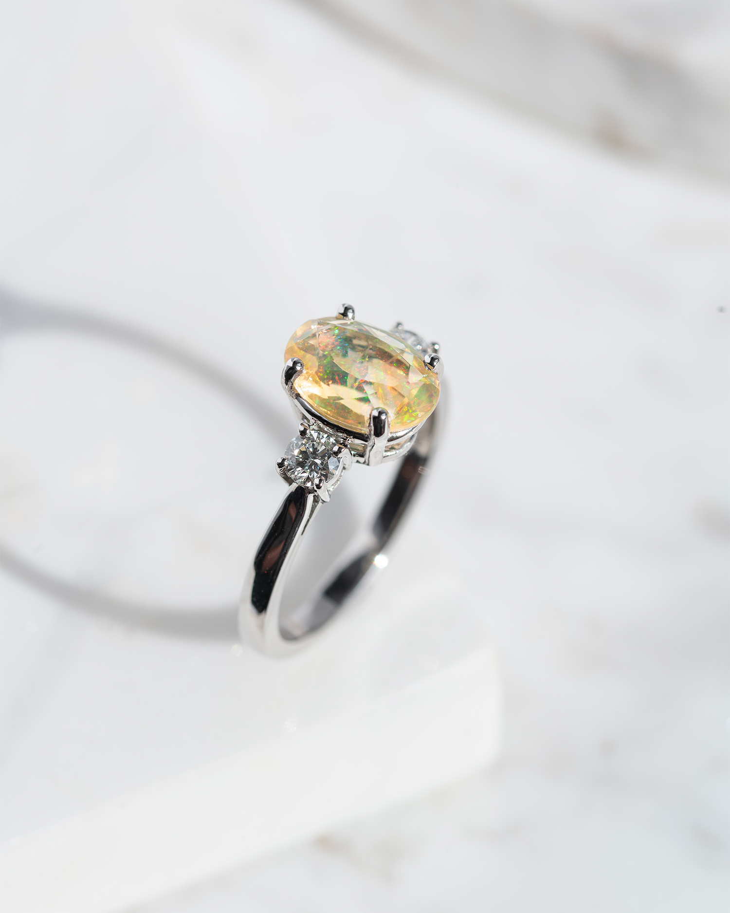 Fire Opal Ring with two diamonds, photographed on a marble base 